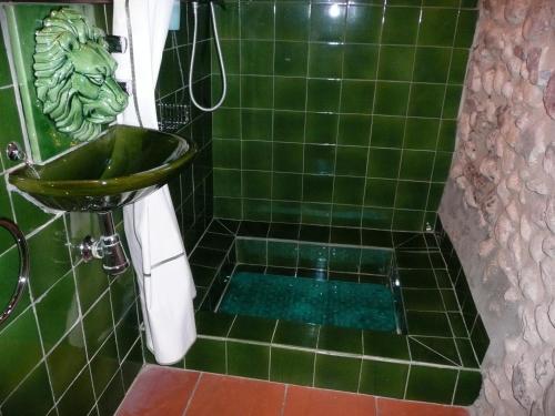 a green tiled bathroom with a green lion head on the wall at CAN TRAVÉ in Crespiá