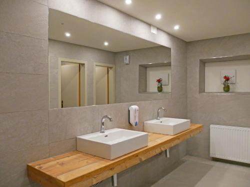 two sinks in a bathroom with two mirrors at Hotel Grieserhof in Lermoos
