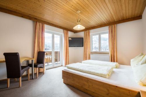a bedroom with a large bed and a desk and chairs at Haus Alpenland in Wagrain