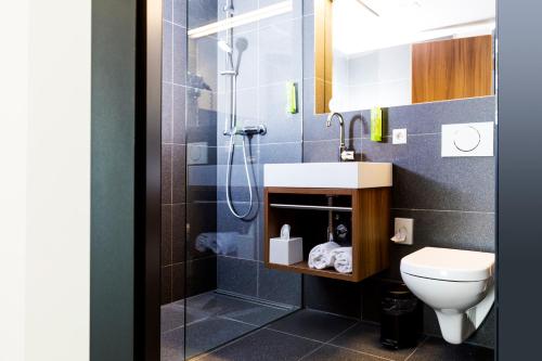 a bathroom with a shower and a toilet and a sink at RiKu HOTEL Weißenhorn in Weißenhorn