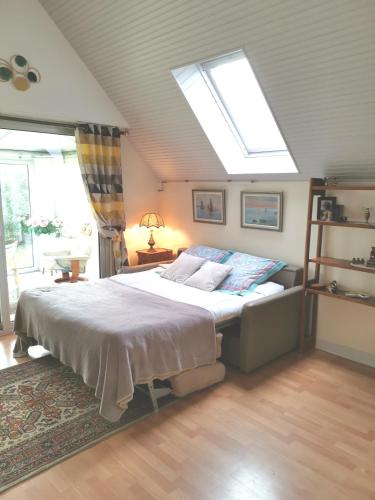 une chambre avec un grand lit avec une lucarne dans l'établissement la frégate blanche, à Concarneau