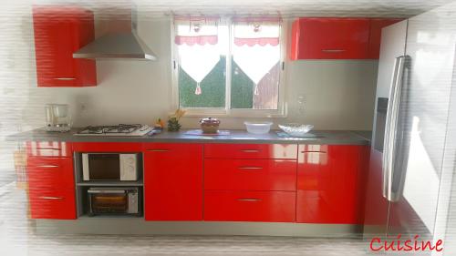 - une cuisine rouge avec des placards rouges et un four micro-ondes dans l'établissement La Maison des Oiseaux, à Eu
