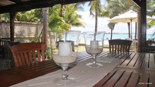 two wine glasses with candles on a table with the beach at Fantastic spacious beachfront VILLAVACANCES in Grand Baie