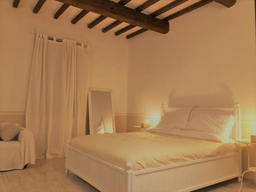 a white bedroom with a bed and a chair at Il Contado -room and breakfast- in Castelfranco Emilia