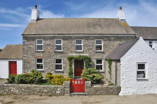an old stone house with a red door at Treleddyn Farmhouse in St. Davids