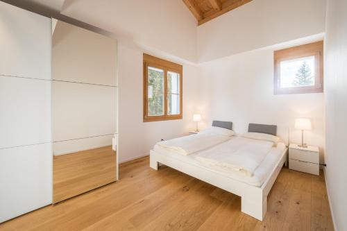 ein weißes Schlafzimmer mit einem weißen Bett und einem Fenster in der Unterkunft LAAX Homes - Taviarna Laax 2,14 in Laax