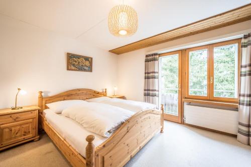 a bedroom with a wooden bed and a window at LAAX Homes - Val Signina 1-13a in Laax