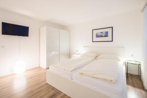 - une chambre blanche avec un lit et une télévision dans l'établissement LAAX Homes - Val Signina 2-9, à Laax