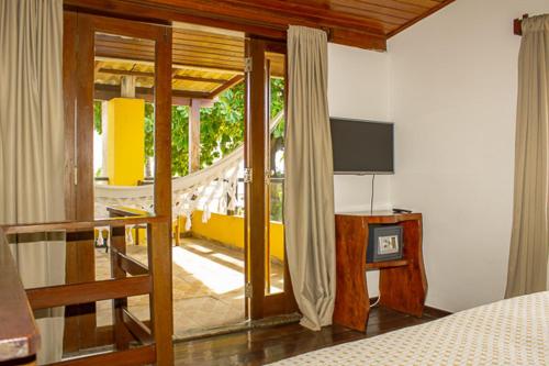 a bedroom with a bed and a balcony with a television at Pousada Funny in Morro de São Paulo