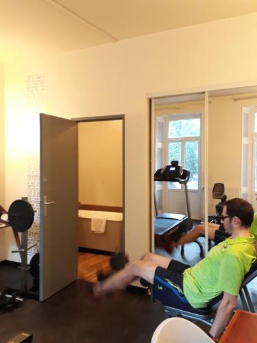 a man sitting in a chair in a room at Hôtel Au Pavillon du Frêne in Lacaune