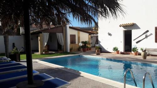 a swimming pool with a palm tree next to a house at Brunelli Residence in Mazara del Vallo