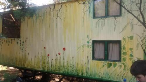 Un vagón de tren con flores pintadas a un lado. en Casilla Rodante Rural en San Marcos en San Marcos Sierras
