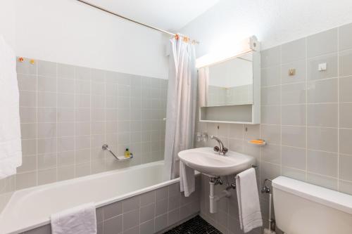 a white bathroom with a sink and a bath tub at LAAX Homes - Val Signina 4-8 in Laax