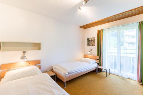 a bedroom with two beds and a window at LAAX Homes - Val Signina 4-8 in Laax