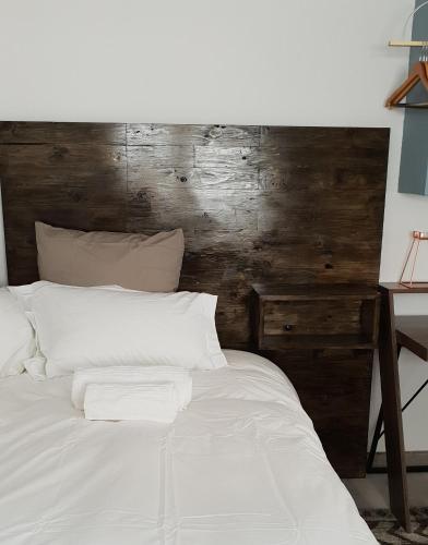 a bedroom with a white bed with a wooden wall at Emmaus Single Room in Bloemfontein