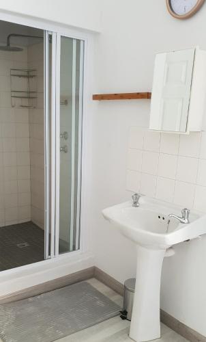 a white bathroom with a sink and a shower at Emmaus Single Room in Bloemfontein
