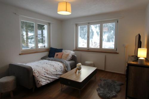 a bedroom with a bed and a table and windows at Haus Siegfried in Churwalden