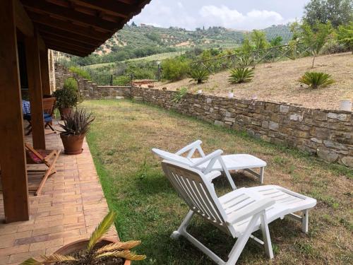 two white chairs sitting on a patio with a stone wall at Casa vacanze Il Mandorlo in Perdifumo