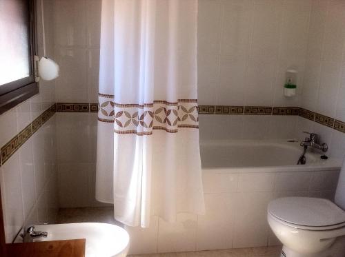 y baño con bañera, aseo y cortina de ducha. en Hostal Madrid Paris, en Buitrago del Lozoya