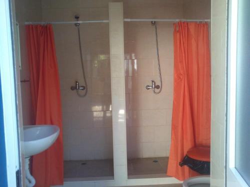 y baño con ducha, cortinas rojas y lavamanos. en Aguarela Tavira, en Tavira