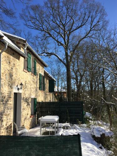 a table and chair in the snow in front of a house at Jouy La longère, proche Hec, Versailles, parking privé gratuit in Jouy-en-Josas