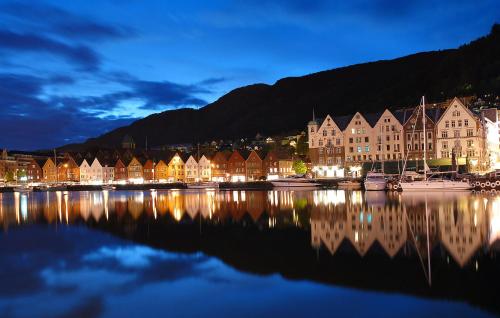 a town at night with its reflection in the water at Central location in the heart of historic Bergen in Bergen