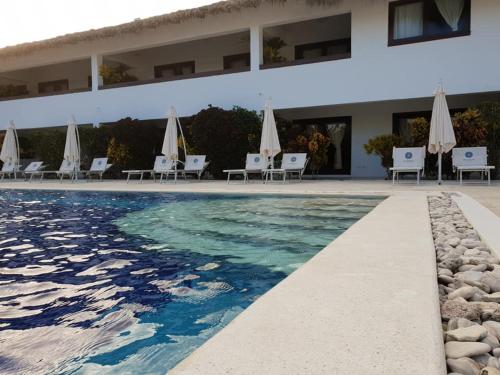 a pool with chairs and umbrellas next to a building at Oasi Encantada - Beach Resort in Santa Cruz de Barahona