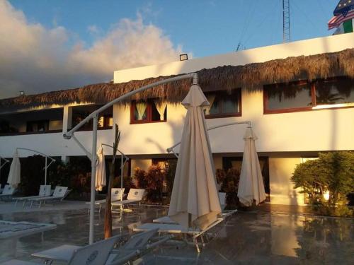 a hotel with chairs and umbrellas in front of a building at Oasi Encantada - Beach Resort in Santa Cruz de Barahona