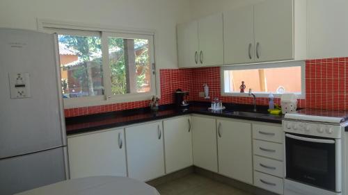 una cocina con armarios blancos y una pared de ladrillo rojo en Casa Perequê 100 metros da praia, en Ilhabela