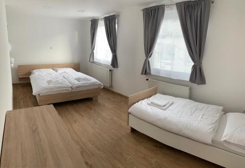 a room with two beds and a table and two windows at Petite Apartment in Maribor