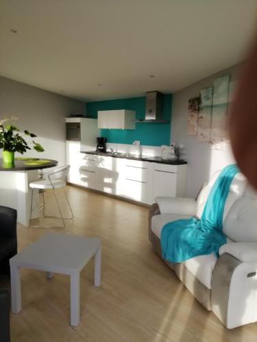 un salon avec un canapé blanc et une cuisine dans l'établissement Les Balcons de Saint Pair, à Saint-Pair-sur-Mer