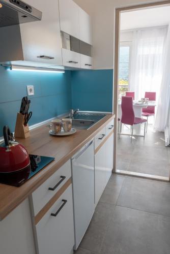 a kitchen with white cabinets and a blue wall at Apartmani Dalmacjia in Grebaštica