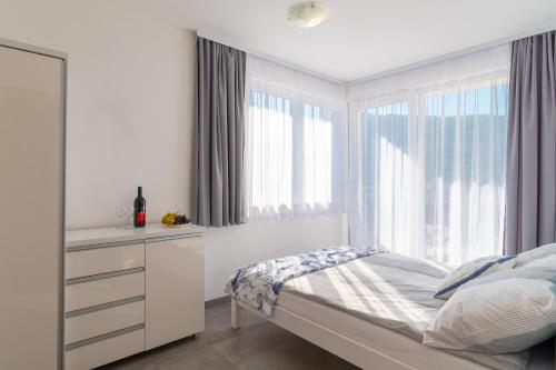 a white bedroom with a bed and a window at Apartmani Dalmacjia in Grebaštica