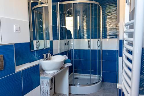 a blue bathroom with a sink and a shower at Apartmani Dalmacjia in Grebaštica
