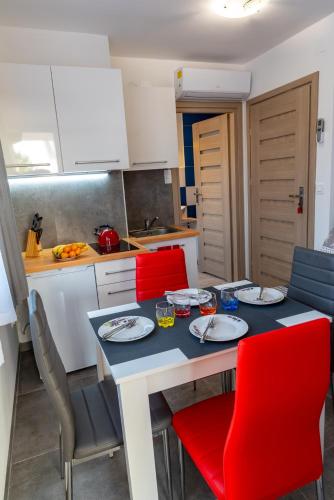a small kitchen with a table and red chairs at Apartmani Dalmacjia in Grebaštica