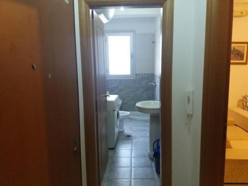 baño con aseo y lavabo y ventana en Vlora Apartment, en Vlorë