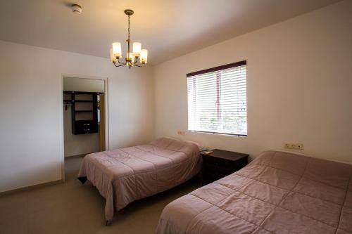 a bedroom with two beds and a window and a chandelier at Blue Bay Apartments in Sint Michiel
