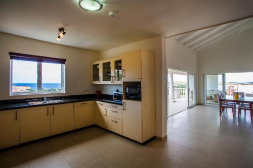 a kitchen with yellow cabinets and a view of the ocean at Blue Bay Apartments in Sint Michiel