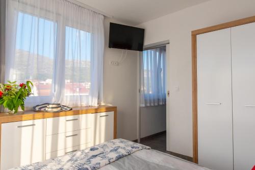 a bedroom with a bed and a tv and a window at Apartmani Dalmacjia in Grebaštica