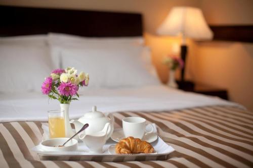 a tray with a breakfast of coffee and flowers on a bed at Best Western Plus Paradise Hotel Dilijan in Dilijan
