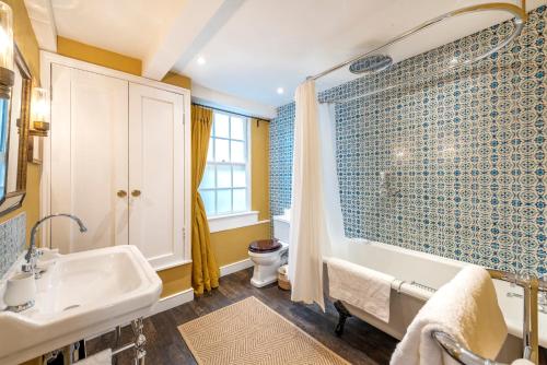 a bathroom with a tub and a sink and a toilet at Stylish & Spacious City Center Georgian Townhouse in Bath