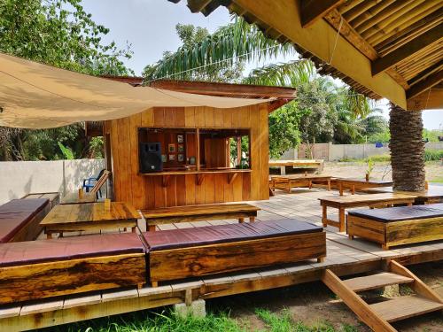 un grupo de mesas y bancos de madera en una cubierta en Laughing Goat Ghana Hostel, en Busua