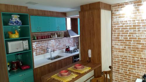 una cocina con armarios verdes y una mesa con sombreros. en Apartamento Espelho das Águas, en Florianópolis