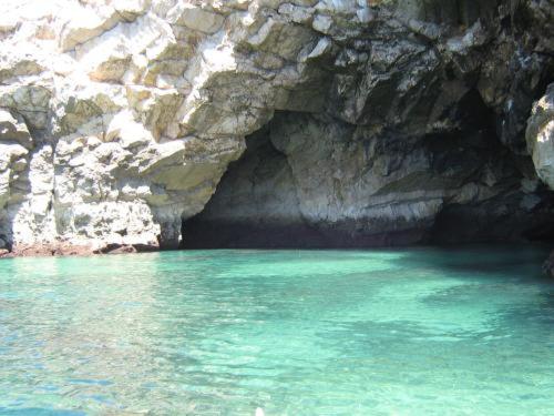 a pool of blue water in front of a rocky cave at Hotel Residencial Salema in Salema