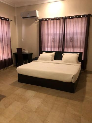 a bedroom with a large bed with white sheets and pillows at Posh Hotel and Suites Ikeja in Ikeja