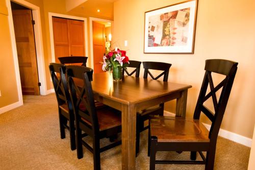 a dining room table with chairs and a vase of flowers at Sundial Hotel in Whistler