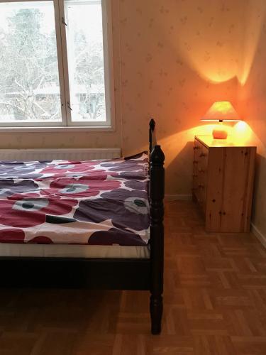 a bedroom with a bed and a lamp and a window at Idyllinen kaksio in Kankaanpää