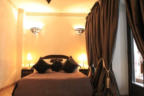 a bedroom with a bed with black pillows at Riad Terra Bahia in Marrakech