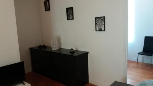 Vestidor negro en una sala de estar con fotos en la pared en Appartement Taïko en La Flèche