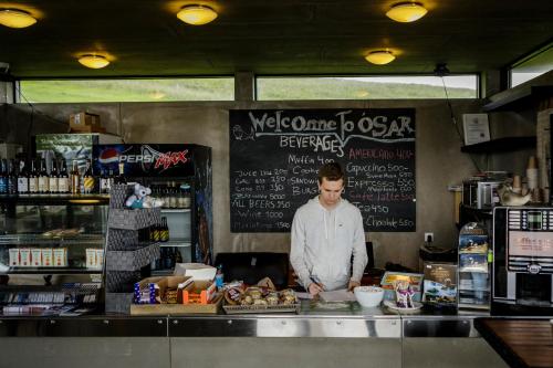 Un uomo in piedi dietro un bancone in una cucina di Ósar Hostel a Tjörn